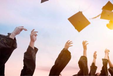 College commencement graduates throw caps in air