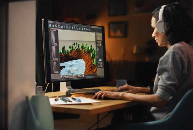 Female video game designer working on desktop computer