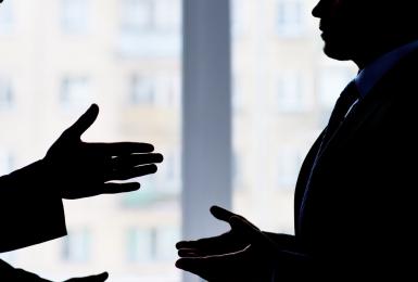 Silhouette of two professionals engaged in conflict resolution.