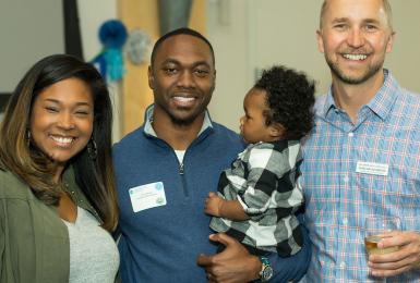 Champlain College graduate with family and staff member at graduation celebration