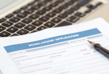 Printed scholarship application lying on laptop keyboard