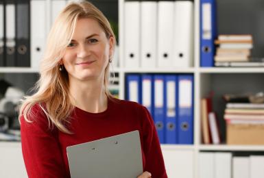 Female health care administration professional smiling in front of bookshelf