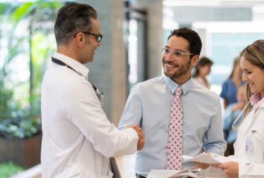 Healthcare administrator shaking hands with doctor in hospital