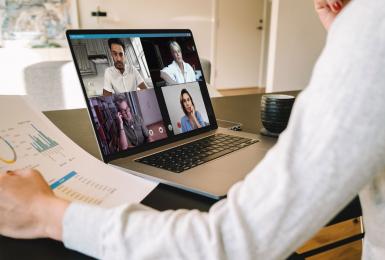 Manager holding video call with remote team on laptop