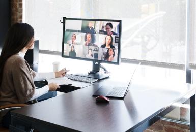 Business woman meeting with colleagues virtually on computer.
