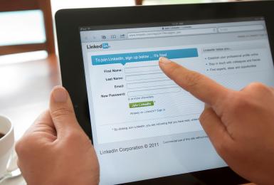 Person holding a tablet and visiting linkedin.com