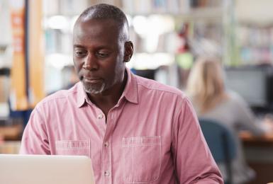 Adult on laptop in a library