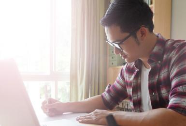 Young student on laptop at kitchen table