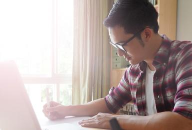 Young student on laptop at kitchen table 