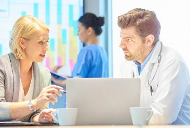 Medical professionals working together in front of a laptop