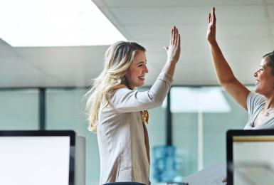 Two professionals giving each other high five in the workplace