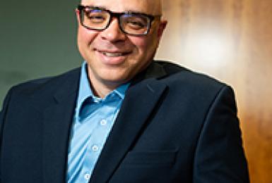 Smiling man standing in conference room wearing business suit and glasses