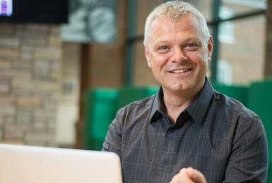 Man sitting in front of computer and smiling at camera