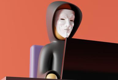 Figure of anonymous man in mask sitting in front of computer