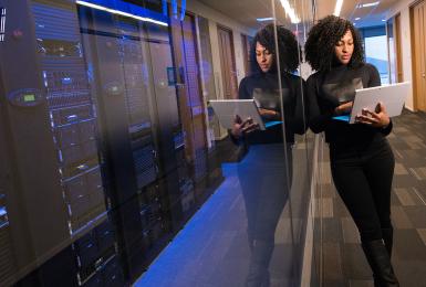 Woman holding laptop with computer lab in background