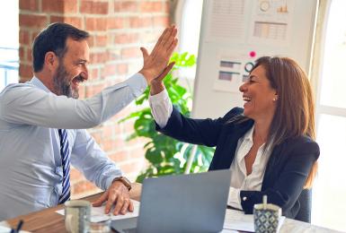 Man and woman high five in an office