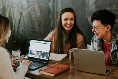 A group of young professionals working on laptops and laughing