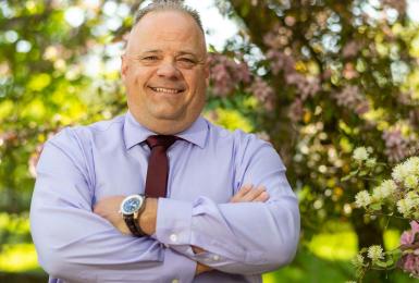 older white male dressed in button down shirt and maroon tie