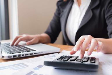 Female accountant using a calculator and laptop