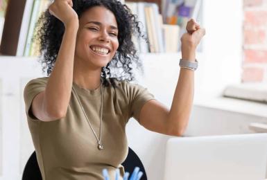 Happy woman celebrating while sitting behind a laptop