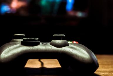 Video game controller on a table in front of blurred TV