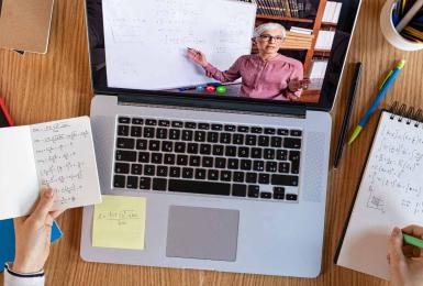 Birds eye view of student working on Macbook laptop taking notes on a notepad