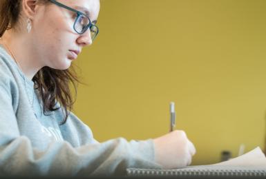 Female student sitting at a desk while taking notes.