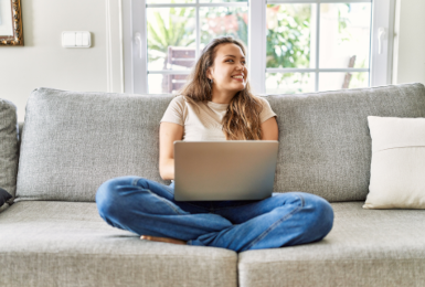 young woman sitting on couch with computer