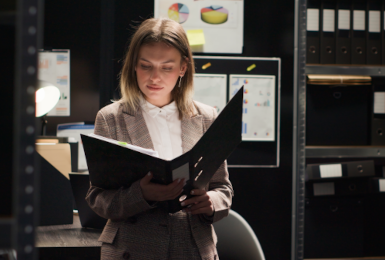 private detective conducting investigation in office, focused on reviewing files and evidence