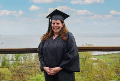 Female graduate dressed in graduation regalia smiling outdoors portrait