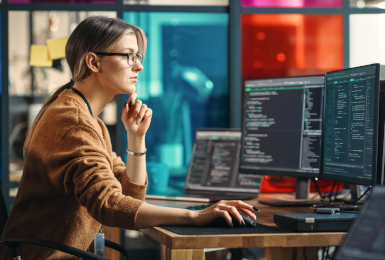 Junior Software Engineer Writes Code on Desktop Computer