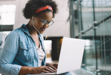university student sitting on a campus bench working on a laptop 