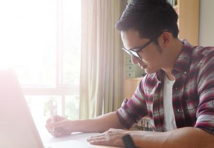 Young student on laptop at kitchen table