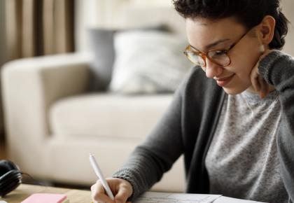 Smiling woman studying and filling out paperwork