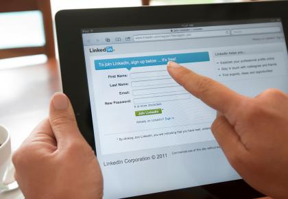 Person holding a tablet and visiting linkedin.com