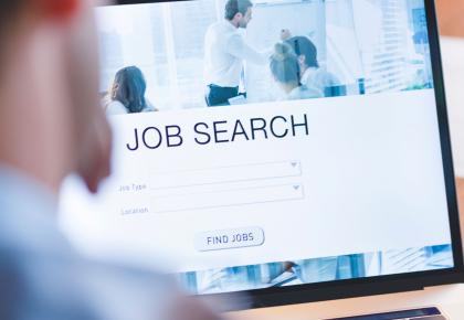 Male professional searching for jobs on laptop.
