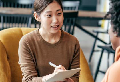 Portrait of two female professionals having an interview and taking notes.
