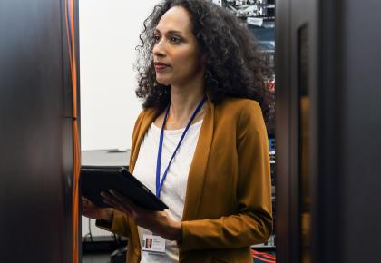 Woman in data center programing mainframe on a digital tablet.