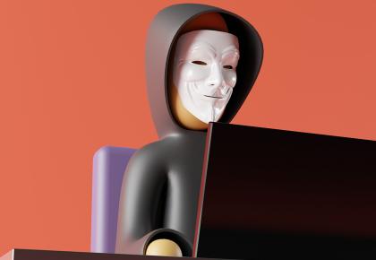 Figure of anonymous man in mask sitting in front of computer