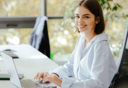 Public administration woman smiling at a desk with a laptop