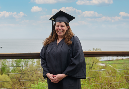 Female graduate dressed in graduation regalia smiling outdoors portrait