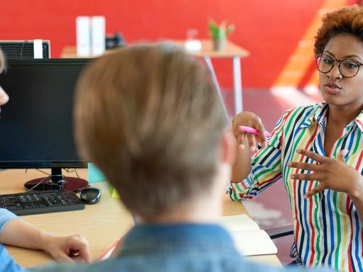 Woman talking to two other people at a desk