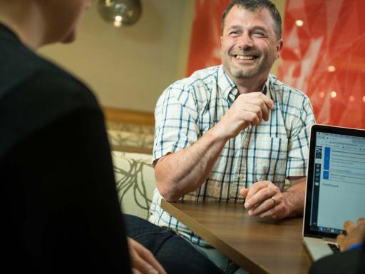 Male student meeting with academic advisors smiling in cafe