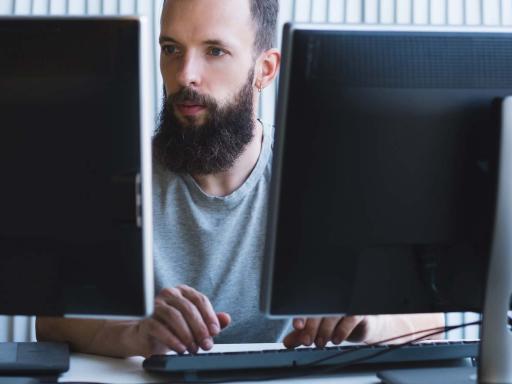 Adult male student work on dual monitors concentrating