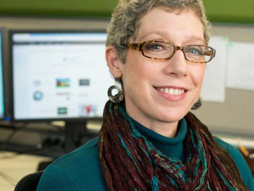 Adult female in front of busy workspace smiling