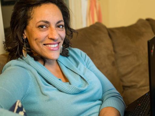 Adult female student working on laptop at home on couch