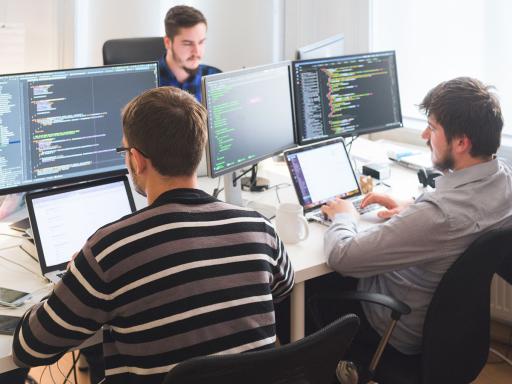 Team of IT professionals at a table of computers working on a project