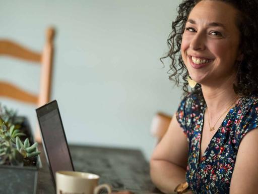 Adult female student working on laptop at dining room table