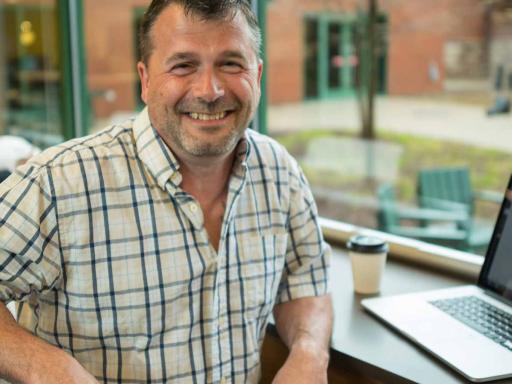 Adult male student with laptop open smiling at camera