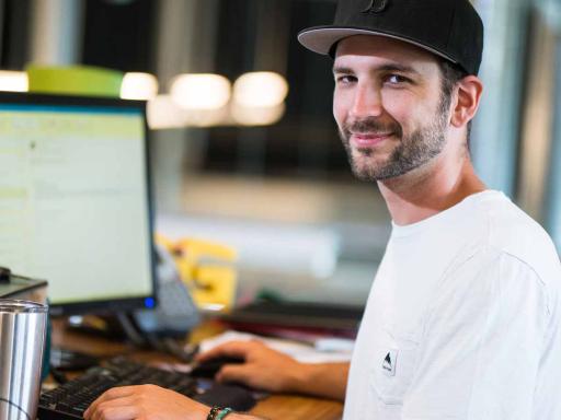 Adult male student at office work station smiling at camera